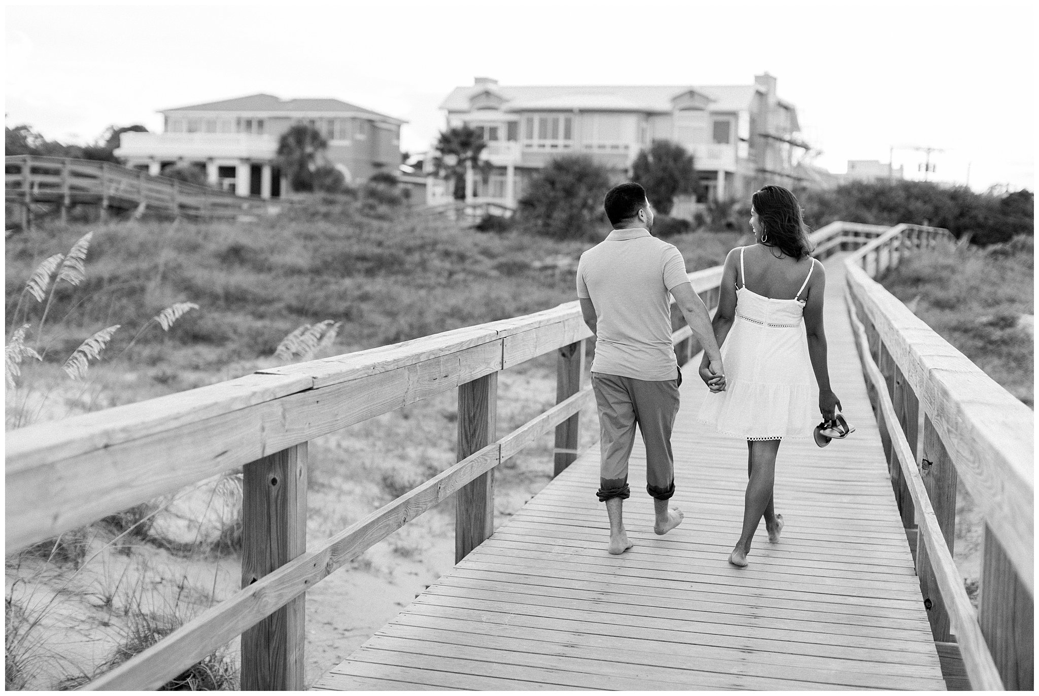 black and white photo Couple holding hands on beach boardwalk